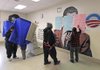A poll worker (right), shows a voter a sample ballot that is covering a mural of President Barack Obama in the voting area of Benjamin Franklin Elementary School polling site Tuesday in Philadelphia. The mural was ordered to be covered after Republicans filed a complaint. 