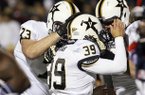 Vanderbilt kicker Carey Spear (39) receives congratulatory helmet slaps from his teammates, including Chase White (73), after kicking the winning extra point in the fourth quarter of an NCAA college football game against Mississippi in Oxford, Miss., Saturday, Nov. 10, 2012. Vanderbilt won 27-26. (AP Photo/Rogelio V. Solis)