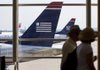 Travelers pass US Airways planes at Reagan National Airport in Washington D.C. US Airways is making its case to merge with AMR Corp.’s bankrupt American Airlines in meetings this week with American Airlines and its creditors. 