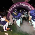 Fayetteville High School players take the field Friday before the Bulldogs’ playoff game with Conway...