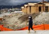 A woman walks past houses under construction in Rancho Cucamonga, Calif., on Sunday. The Commerce Department said housing starts in October rose to a four-year high. 