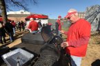 Mike Moffett of Fayetteville checks on a piece of meat he was smoking Friday while tailgating with friends before the University of Arkansas football game with Louisiana State in front of Bud Walton Arena in Fayetteville.