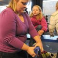 Tasha Martin, left, helps daughter Grace Martin slip on a pair of ice skates Saturday at the Jones C...