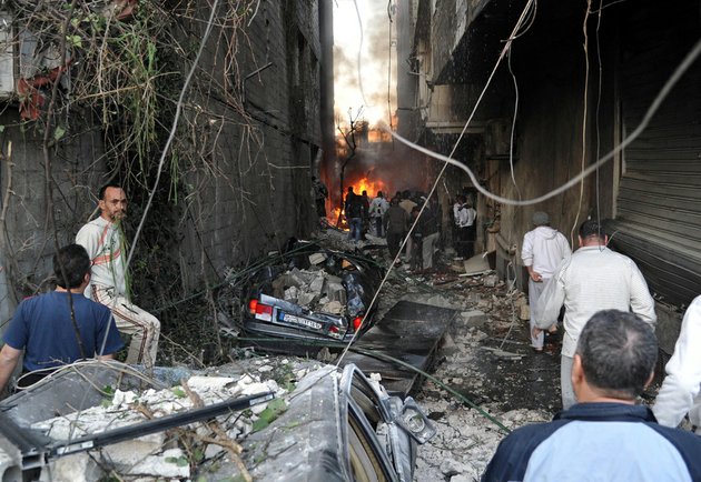 in-this-photo-released-by-the-syrian-official-news-agency-sana-syrian-citizens-gather-at-an-alley-destroyed-by-two-cars-bombs-in-the-jaramana-suburb-of-damascus-syria-on-wednesday-nov-28-2012