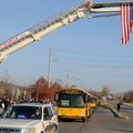 Buses carrying members of the Fayetteville High School football team pass under a flag Friday, Nov. ...
