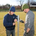 Ferguson, (left) right, assists Henson install poles in outfield at Veterans Park. 