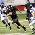Reece Dollins, center, Bentonville quarterback, squeezes in between a hole in Fayetteville’s defense...