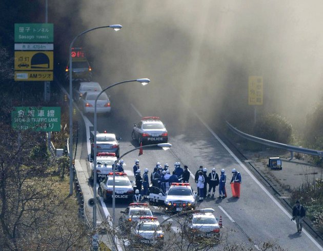police-vehicles-are-parked-at-the-entrance-as-smoke-billows-out-of-the-sasago-tunnel-on-the-chuo-expressway-in-koshu-yamanashi-prefecture-central-japan-sunday-morning-dec-2-2012-a-part-of-the-tunnel-collapsed-sunday-morning-possibly-involving-several-vehicles-and-injuring-several-people-local-media-said