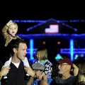 McKayla Caywood, 18 months, waves as she sits on the shoulders of her father, Clay Cawood, to watch ...