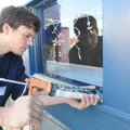 Tyler Ramsey of Rogers caulks around a glass pane Tuesday while remodeling a downtown Rogers storefr...