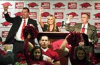 New Arkansas head coach Bret Bielema, left, his wife, Jen, center, and athletic director Jeff Long, right, Call the Hogs during an NCAA college football news conference in Fayetteville, Ark., Wednesday, Dec. 5, 2012. (AP Photo/April L. Brown)