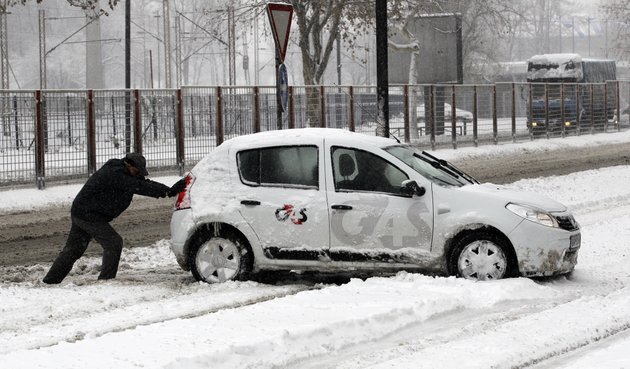 a-man-pushes-a-car-on-a-snow-covered-street-in-belgrade-serbia-sunday-dec-9-2012-freezing-temperatures-and-heavy-snowfall-have-killed-at-least-5-people-and-caused-travel-chaos-across-the-balkans