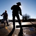 Kent “Woody” Porter, right, and Jack Young, both with Action Seal Coating in Lowell, seal coat the p...
