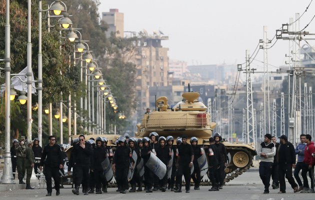 egyptian-riot-police-walk-past-a-military-tank-guarding-the-presidential-palace-in-cairo-egypt-sunday-dec-16-2012-key-egyptian-rights-groups-called-sunday-for-a-repeat-of-the-first-round-of-the-constitutional-referendum-alleging-the-vote-was-marred-by-widespread-violations-islamists-who-back-the-disputed-charter-claimed-they-were-in-the-lead-with-a-majority-of-yes-votes