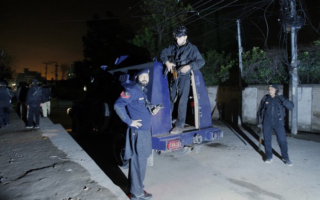 pakistani-police-officers-gather-beside-an-armored-vehicle-near-the-site-of-rocket-attack-by-militants-in-peshawar-pakistan-on-saturday-dec-15-2012-militants-fired-three-rockets-at-an-airport-in-the-northwestern-pakistani-city-of-peshawar-on-saturday-night-killing-several-people-and-wounding-dozens-officials-said