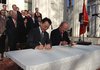 Carlos Westendorp, right, Club de Madrid Secretary General and Eugene Yun, left, Managing Director of the P-80 Foundation, sign the Little Rock Accord in front of the Old State House in downtown Little Rock.