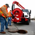 Johnny Lunsford, left, removes the manhole cover while Pat Sharp, both with Rogers Water Utilities, ...