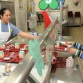 Sonja Martinez, left, helps Travis Emios, 5, with his tray of breakfast food Nov. 30 at Bayyari Elem...
