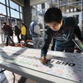 Willy Butihi, a junior at Heritage High School, signs a banner that reads “Our Thoughts Are With You...