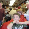 Ryan Howk, foreground, checks out his haircut Saturday after getting trimmed by barber Gary Townzen,...