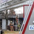 Fire crews from Centerton, Bentonville and Highfill climb on top of the roof Monday after responding...