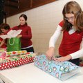 Lily Agnacian, 12, right, secures wrapping paper with a piece of tape Monday while wrapping presents...
