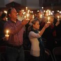 Shawn Blakemore of Fayetteville holds aloft a candle Monday while singing alongside his 9-year-old s...