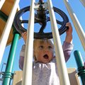 Pilot Miller, 15 months, turns a steering wheel on the playground equipment at Wilson Park in Fayett...
