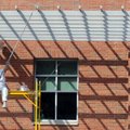 Jose Solano, with CertaPro Painters, paints an overhang Friday, Sept. 28, 2012 on the east side of t...