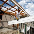 71B Auto Auction employees Shane Wood, and Jared Mitchell toss aside roof and awning pieces from the...