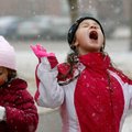 Addyson Ogle, 6, and her sister, Amaya Ogle, 4, try to catch snowflakes Friday outside their home in...