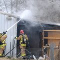 Springdale firefighters douse hot spots Friday during a shed fire behind a home on South Scott Hollo...