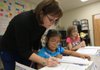 Third-grade teacher Johnnie Brock checks the work of 8-year-old Bernice Antunez (center) and Trista Black, 9, during a recent Direct Instruction period at De Queen Elementary School. 