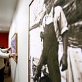 Chris Engholm of Bentonville hangs a piece of art on the wall Thursday at the Arts Center of the Oza...