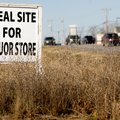 Motorists pass along West Walnut Street on Friday in Rogers past a sign promoting property for sale ...