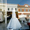 Downtown businesses are reflected in the storefront windows Friday of White Dress Boutique. Owner La...
