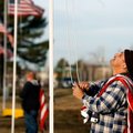 Maintence worker Marlin (cq) Johnson hoists an American flag outside the Benton County Memorial Park...
