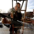 Chris Wallace of Paneless Window Cleaning in Fayetteville cleans glass outside Arvest Bank on Friday...