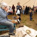 Longtime artist Maeve Courteau of Elkins, left, takes a break Saturday from making wooden spoons to ...