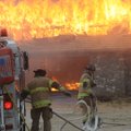 Kevin Chapell, left, and Michael Dean, Rogers Firefighters, bring a hose toward flames Tuesday durin...