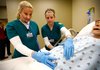 Shelly Lee, left, of Fayetteville and Jessica Abramson of Springdale check Friday on a pregnant dummy at the Center for Health Professions building at NorthWest Arkansas Community College in Bentonville. The school held a grand opening ceremony for the 83,000-square-foot building. Classes began in the new building Monday.