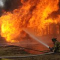 Aaron Thomas with the Rogers Fire Department turns away from the heat Friday during the demolition o...