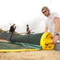 Kaleb Reynolds, ball field foreman with Springdale’s Parks Department, rolls up a temporary outfield...