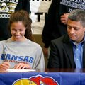 Tayler Estrada signs her letter of intent on Wednesday as her father, Doug Estrada, watches inside t...