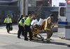 Emergency personnel work with University Police Department officers Friday to load a patient into an ambulance after a report of a man who suffered an accidental self-inflicted gunshot wound to his hand at the KUAF studio.