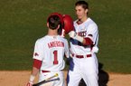 Arkansas first baseman Eric Fisher is greeted by teammate Brian Anderson as he crosses home plate after a solo home run in the third inning of Friday afternoon's season opener at Baum Stadium in Fayetteville. 