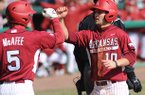 Arkansas' Joe Serrano (10) is congratulated at the plate by Brett McAfee after scoring a run and recording and RBI Saturday, Feb. 16, 2013, during the sixth inning of the Hogs' win over Western Illinois at Baum Stadium in Fayetteville.