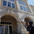 Daniel Garcia of Bella Vista washes windows Tuesday at the Benton County Courthouse on the Bentonvil...
