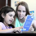 Anna Bever, right, child care coordinator with the Jones Center’s after-school program, reads a book...