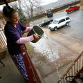 Dianna Dauzart pours hot water along the steps leading to her apartment Thursday in hopes of melting...